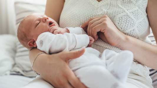Mom holding newborn baby wearing white suit