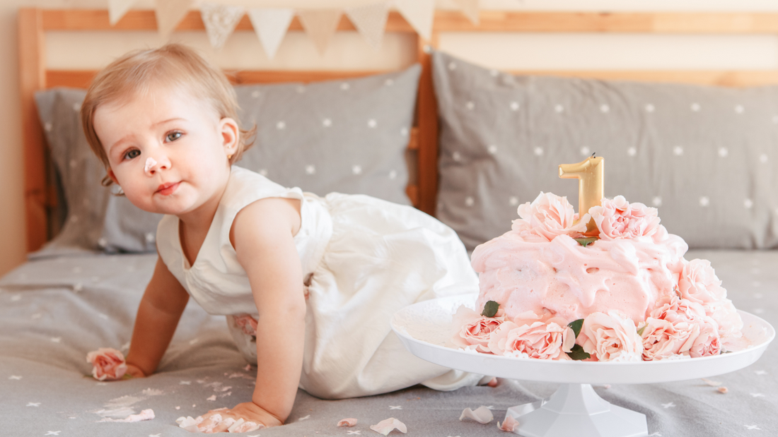 baby crawling with first birthday cake next to her