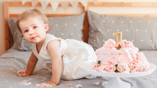 baby crawling with first birthday cake next to her