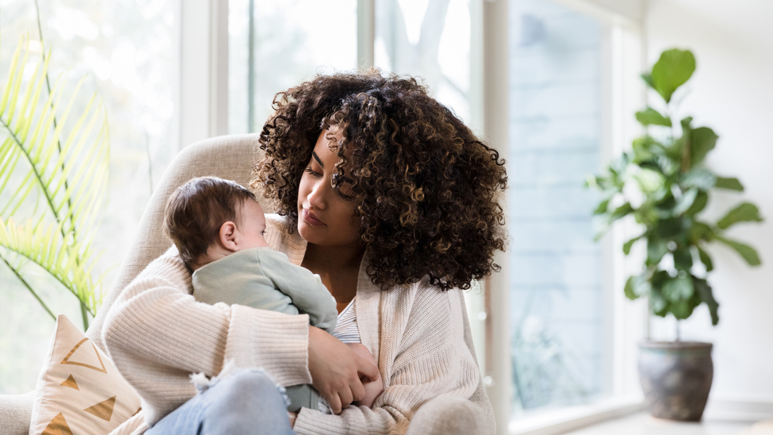 mom cuddling baby on the couch near window