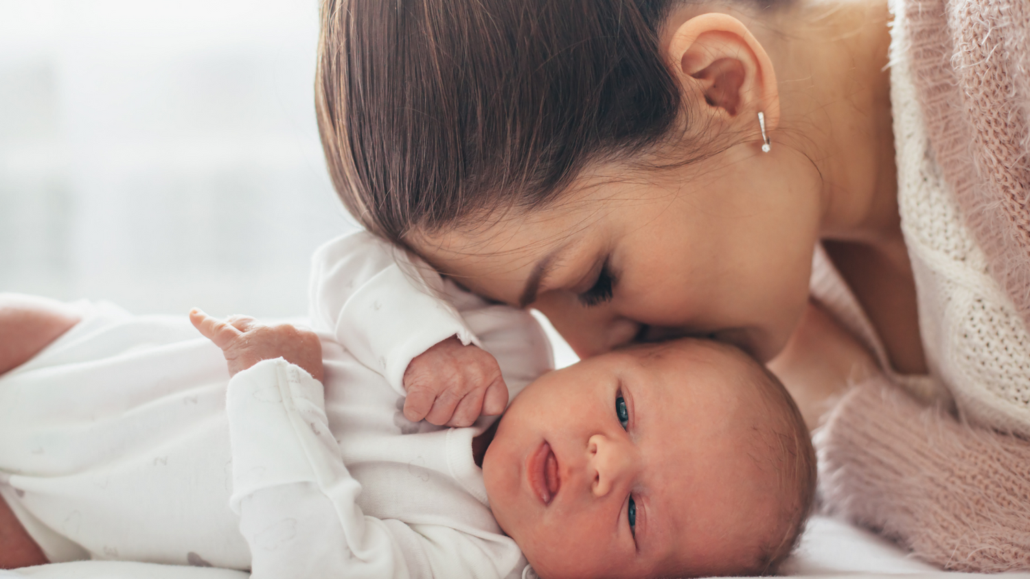 Mum kissing baby after finishing baby journal