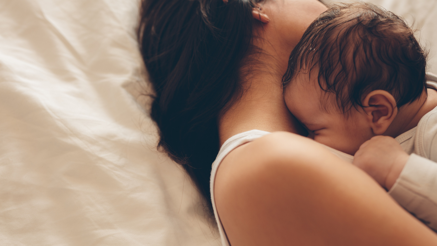 Mum cuddling baby in bed 